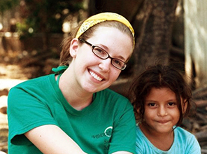 College student smiles and sits beside a young child