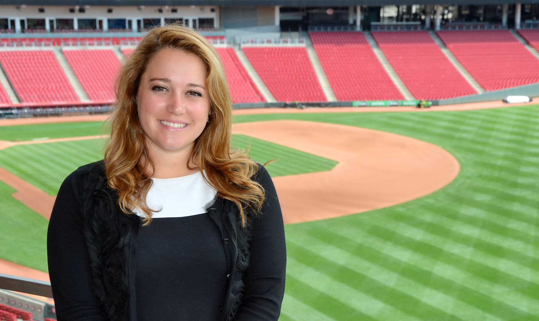 woman pictured with baseball field behind her