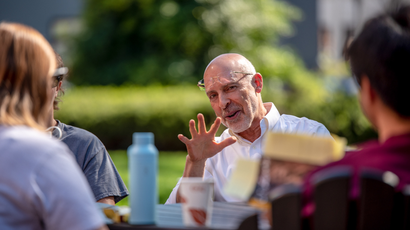 Professors and students sitting around a table and talking