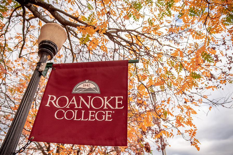 A Roanoke College banner hangs from a lamppost