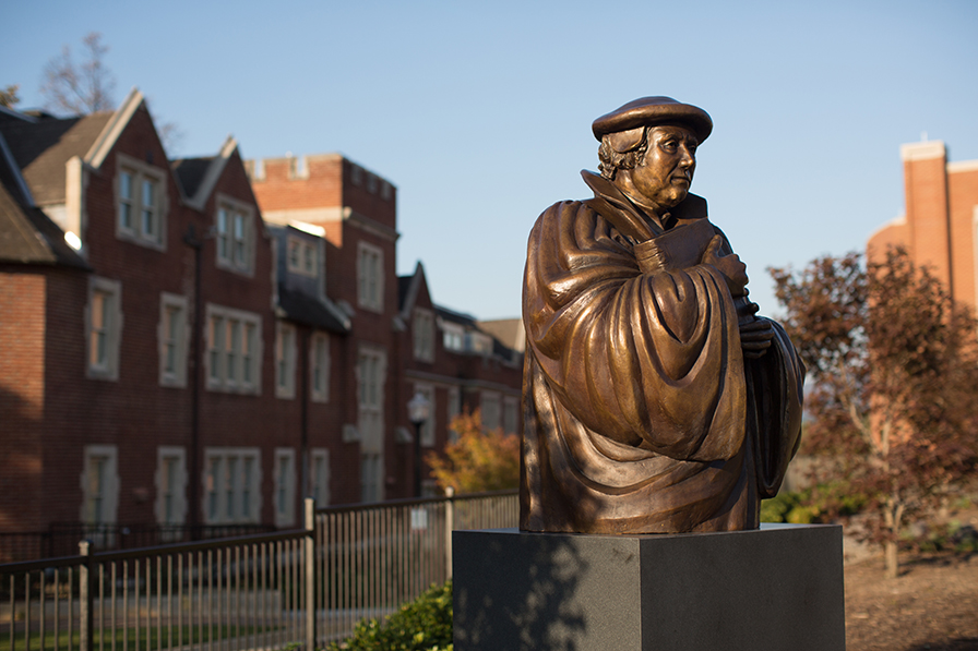Bronze sculpture of Martin Luther with a brick dormitory in the background