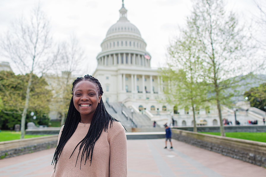 A young woman stands with the nation's capitol building in the background.