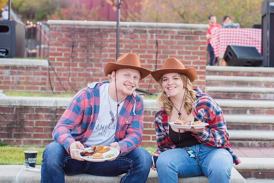 Two students in matching brown cowboy hats and plaid shirts smile for the camera