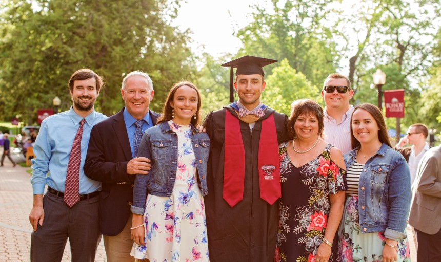 A Student in graduation regalia with family members