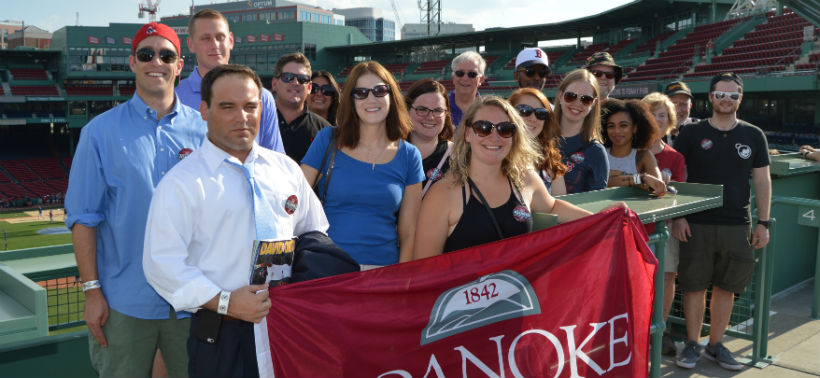 Roanoke College Alumni take picture with the College's flag at a Red Sox game