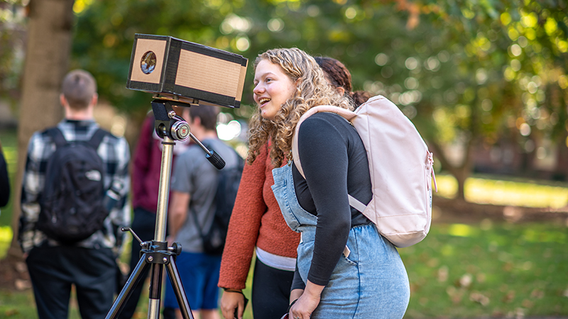 student looking at camera obscura