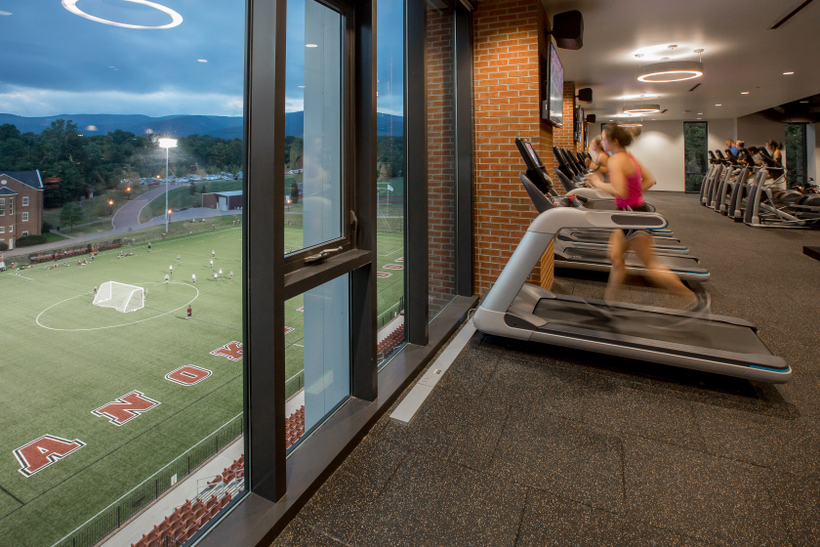 Students in the workout center in the Cregger Center by large windows