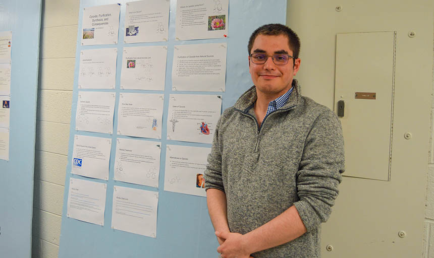 A student in front of a poster displaying his work