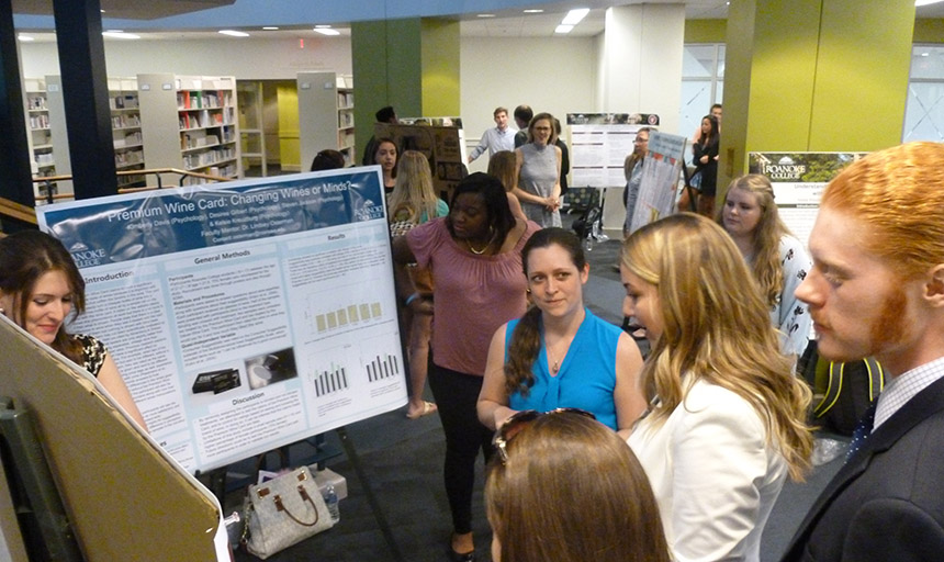 people crowded around a poster board presentation