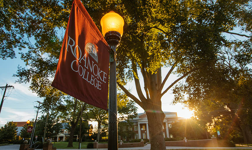 A Roanoke College flag flying with Fintel library in the background
