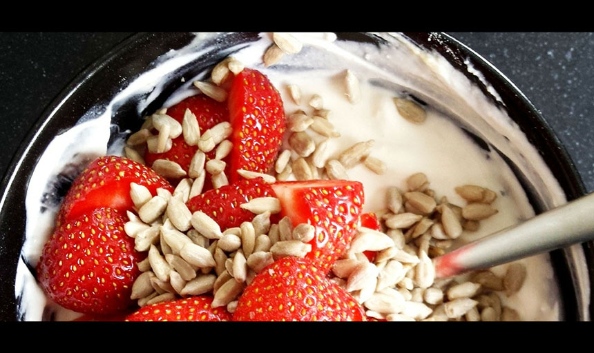 A picture of yogurt with granola and strawberries