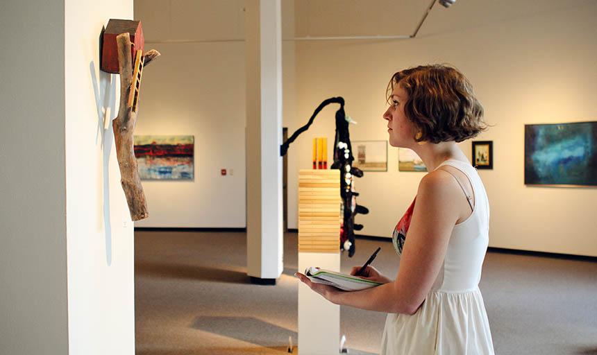 A student admiring a piece of art and writing in a notebook