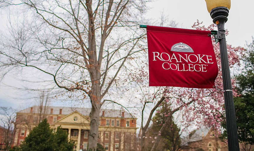 A roanoke college banner with the administration building in the background