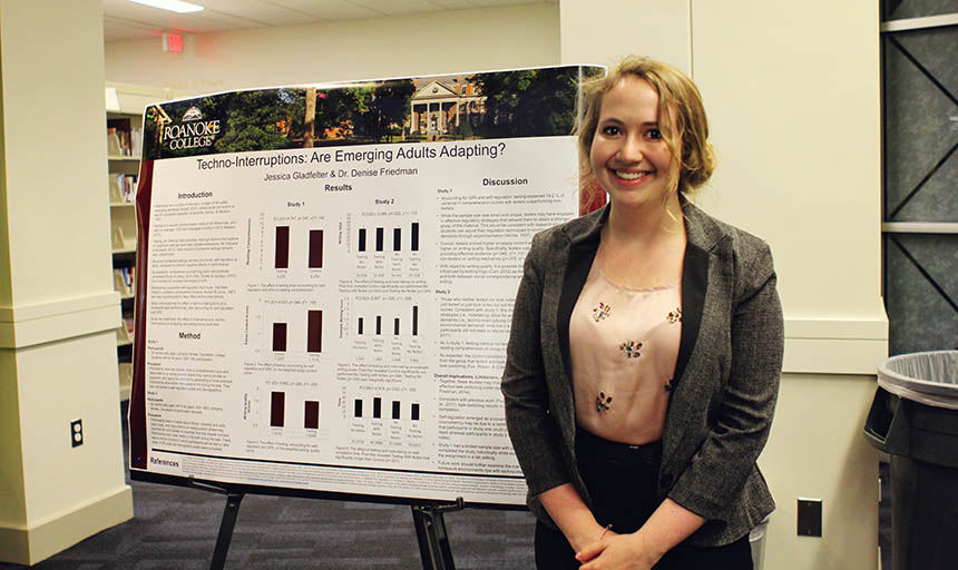 A student standing next to a poster with her research findings on it