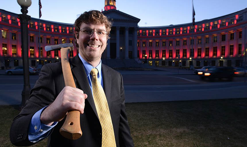 Scott Segerstrom holding an axe in front of a building
