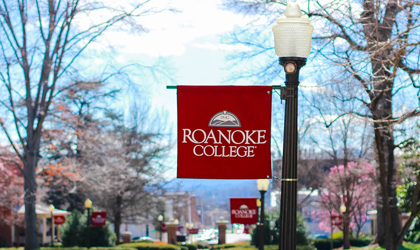 A roanoke college banner with blooming trees in the background
