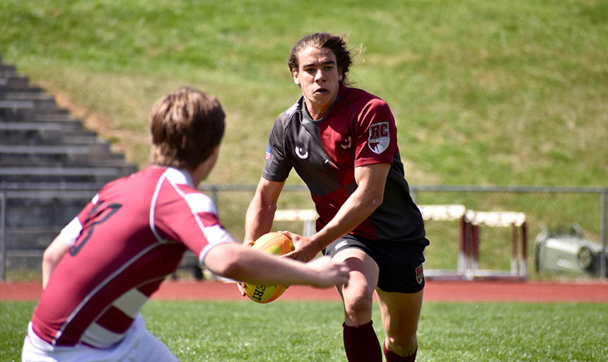 A member of the men's rugby team running with the ball