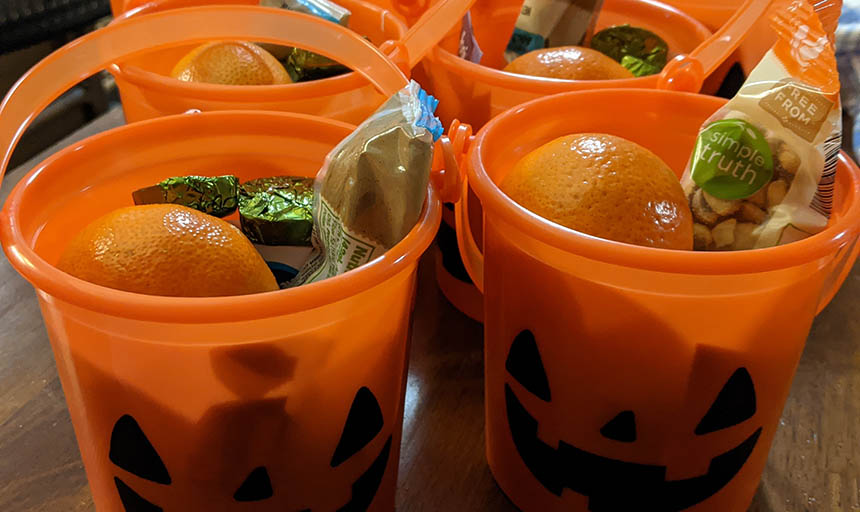 Orange pumpkins with jack-o-lantern faces filled with fruit, nuts, and candy