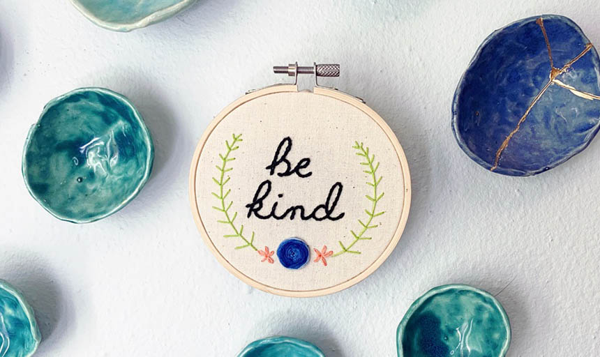 An embroidery project that says "Be kind" with a flower at the bottom