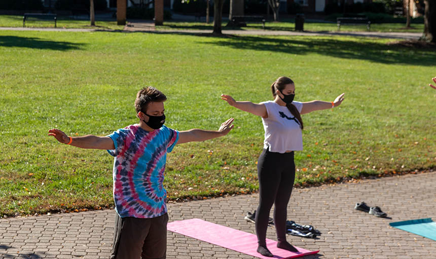 Students in masks doing yoga on the back quad
