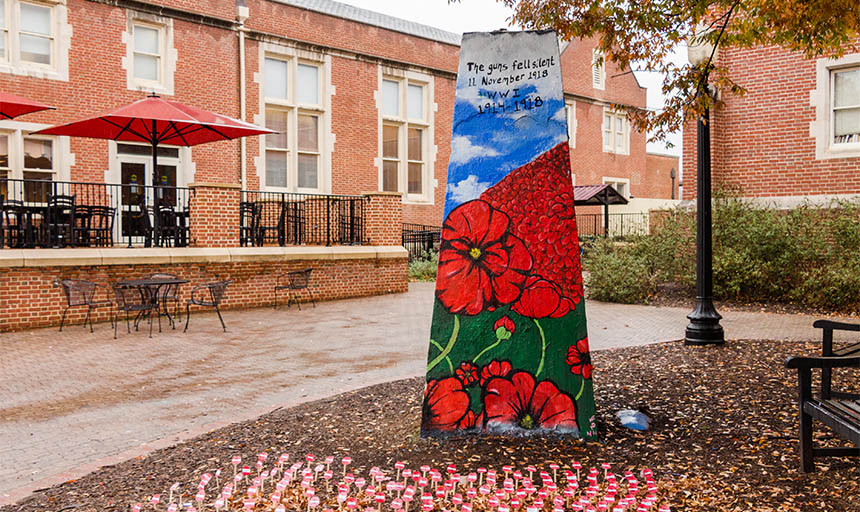 Photo of the large rock on campus painted with a field of red poppies and blue sky