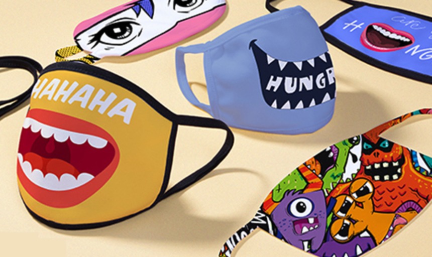 Customized Face Masks sitting on a table. Some have cartoon mouths and others have cartoon eyes