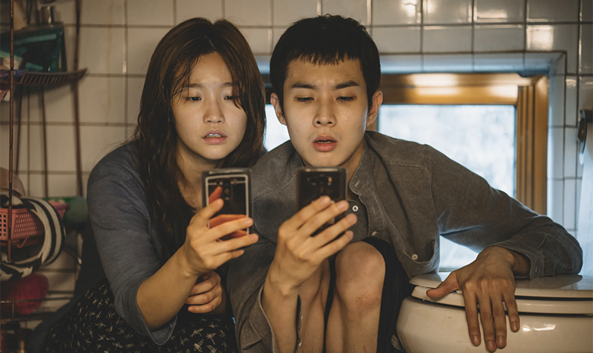 Two characters sitting on the floor of the bathroom looking at their phones