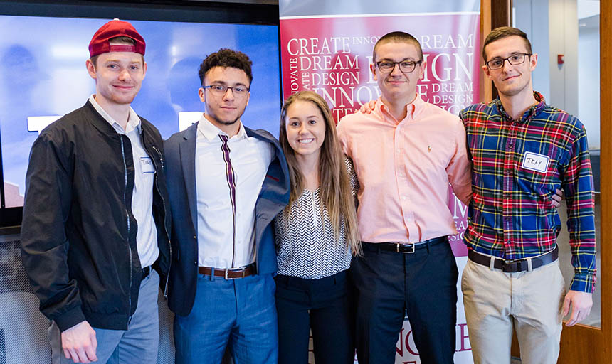 Five students standing in business casual attire