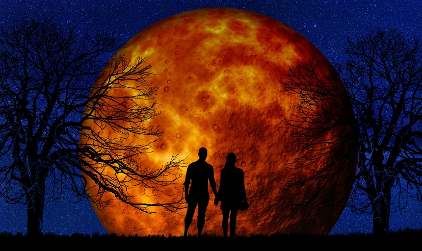 two people stand in front of a red moon