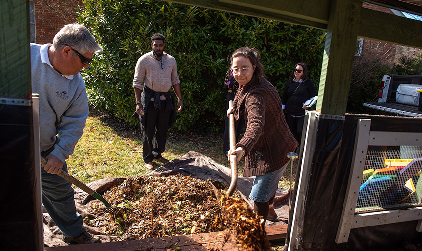 college employees shovel compost at the campus garden