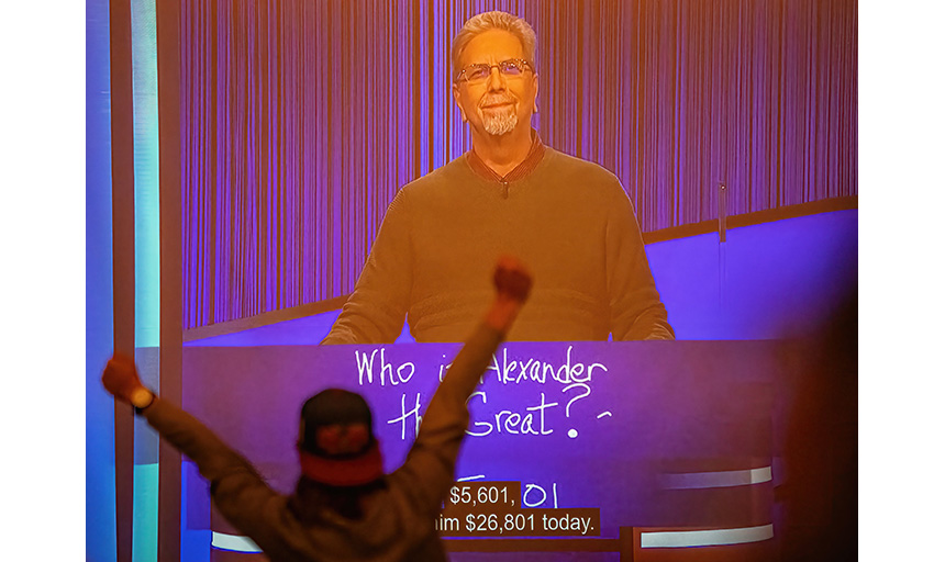 A student at a Dec. 8 campus watch party cheers with arms raised in exuberance when Dr. Hollis wins his initial tournament appearance on Jeopardy