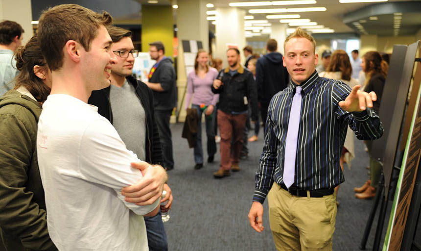 A student explains his work to other students during a research poster presenation at Fintel Library