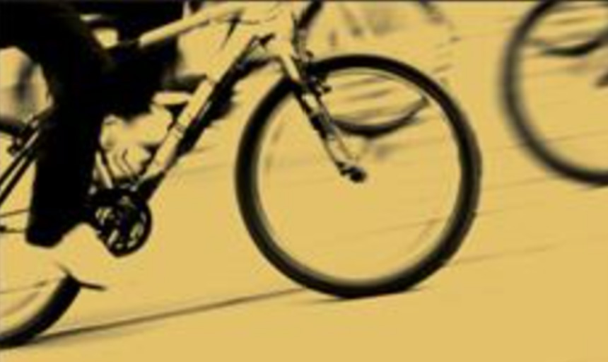 A black-and-white image of feet pedaling a bicycle