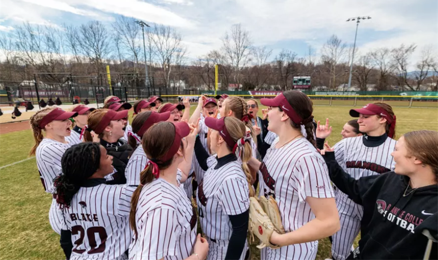 RC softball team celebrating in a huddle