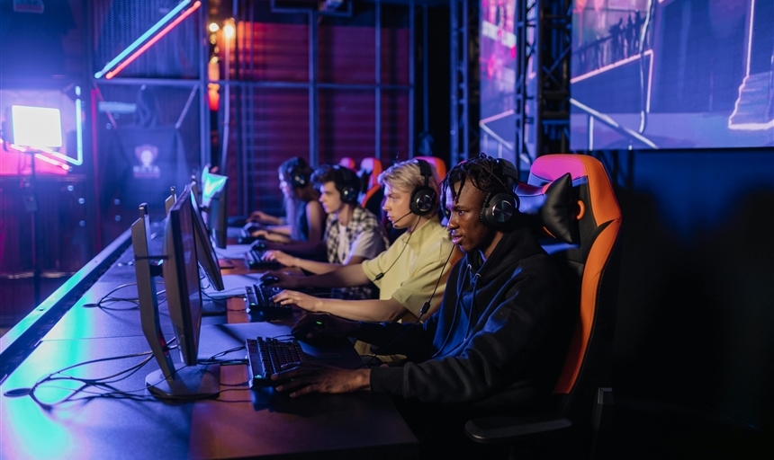 four people gaming in front of screens in a dark lit room