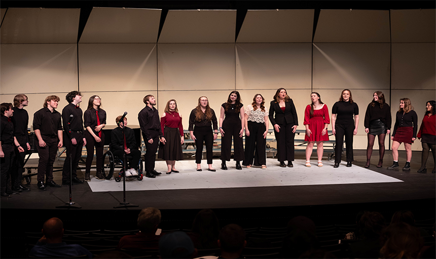Students lined up on stage singing in a choir concert.