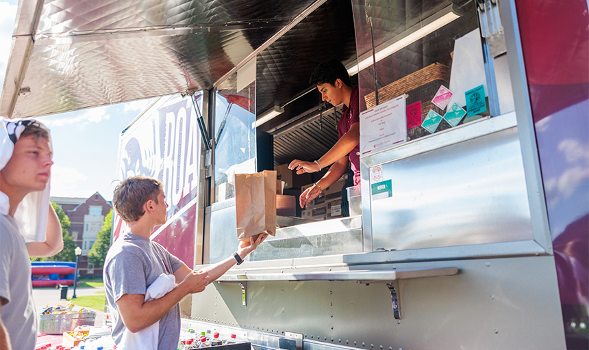 Student handing another student food from RC food truck