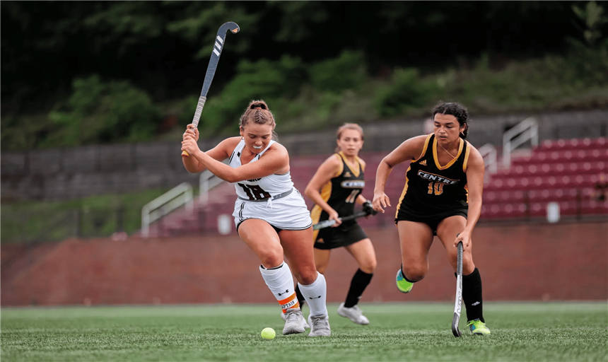picture of woman with field hockey stick about to hit a ball 