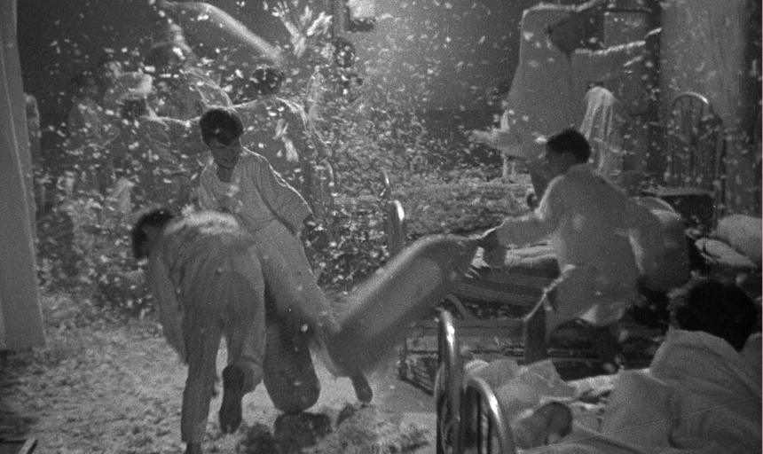 Feathers fly through the air while young boys engage in a pillow fight