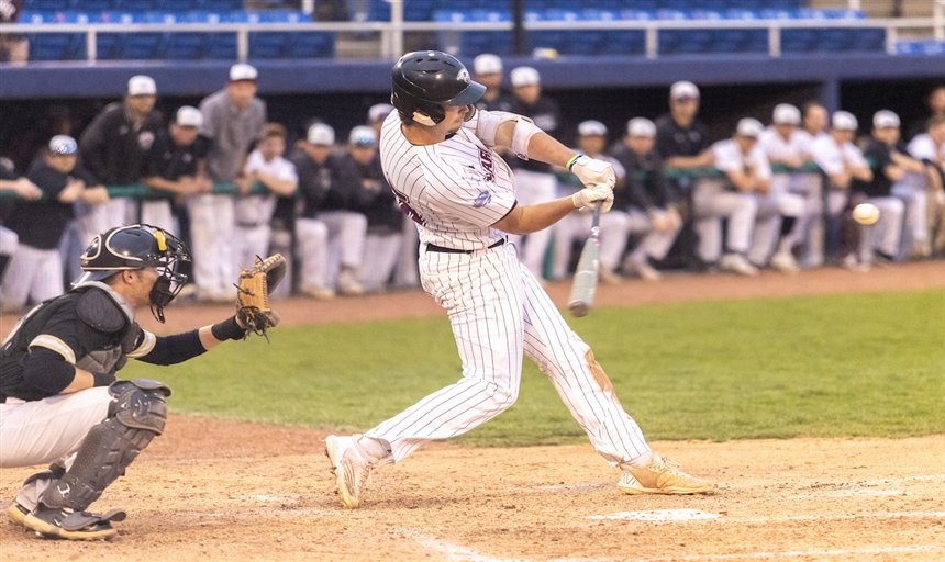 photo of a baseball player in a white uniform hitting the baseball with a bat.