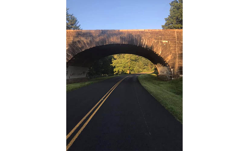 the sun shines across a tunnel that bridges over the road