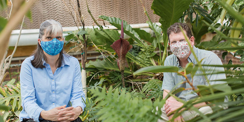 two professors sit among plants framing a large flower