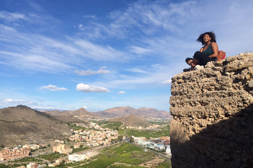 Student sitting on a wall overlooking a town
