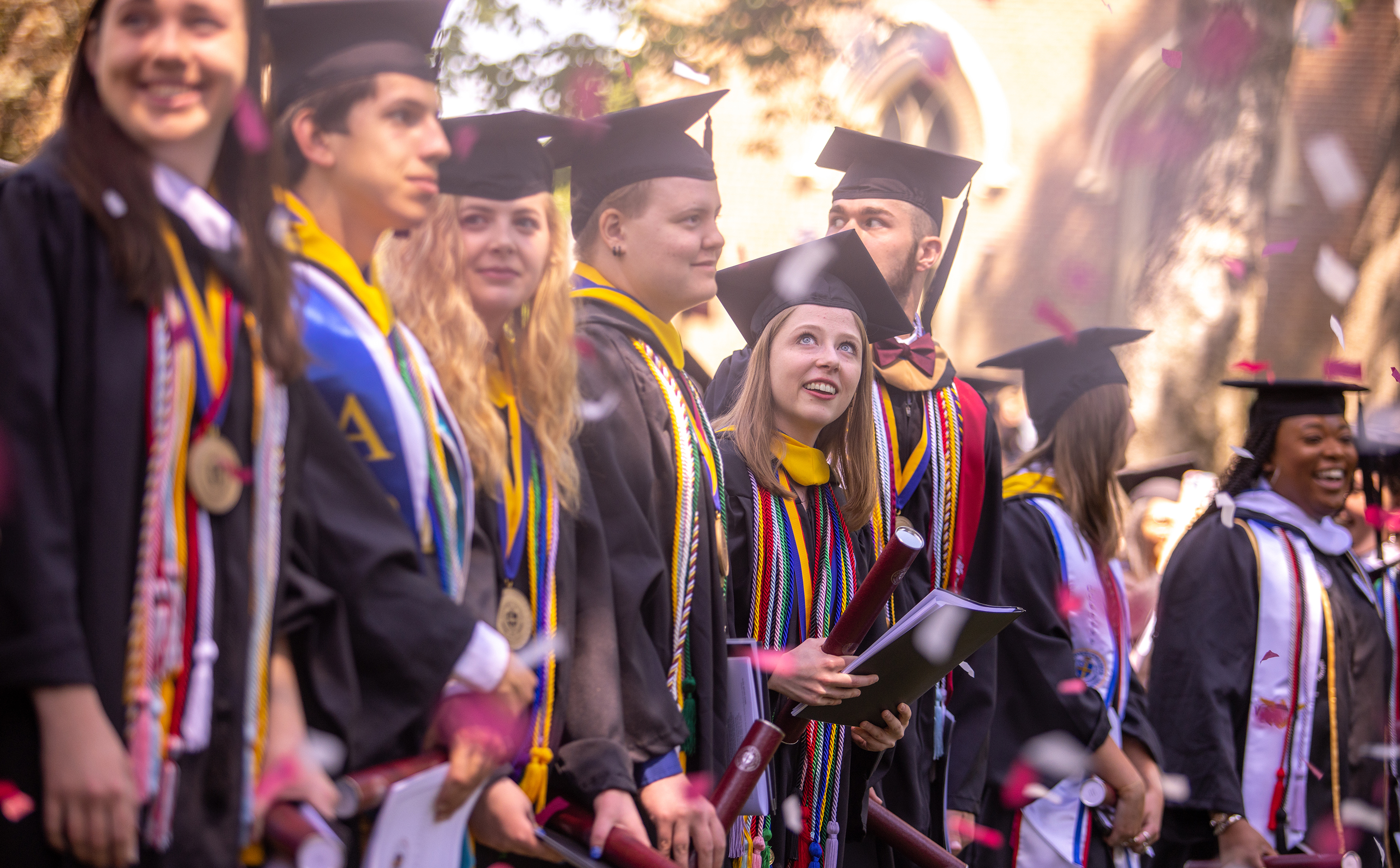 Students at commencement with confetti falling around them