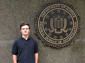 Student standing next to the FBI seal on a building