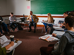 Students in a circle having a discussion with their professor