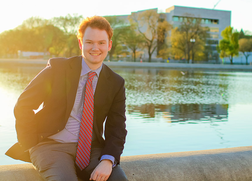 Student posing for a photo by the reflecting pool