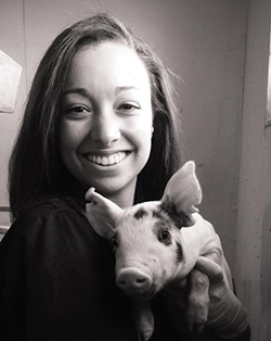 Photo of Tyler Barnes with a small pig