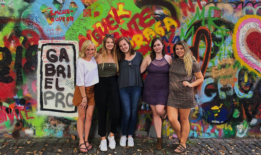 Students standing in front of a wall covered in colorful graffiti
