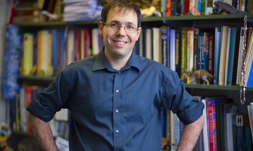 A photo of Chris Lassiter in front of a bookshelf